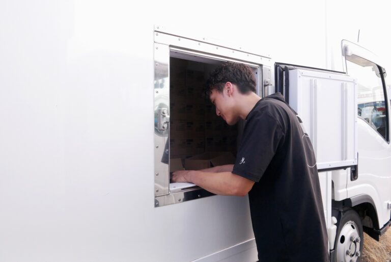 配送用の冷凍トラックの温度を下げないため、補充時には小さな窓から商品を出し入れする。